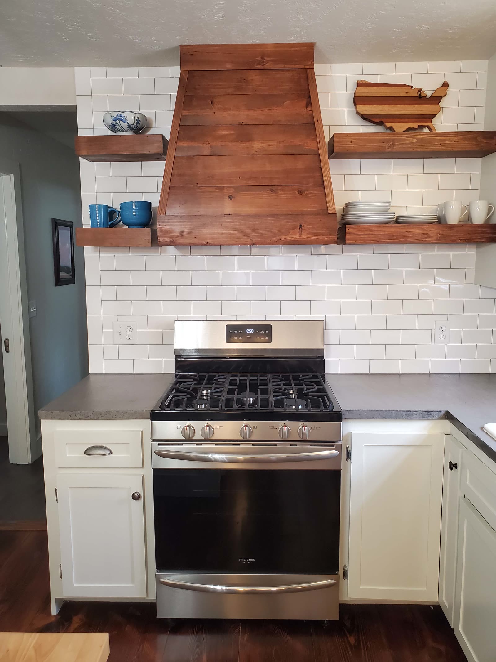 Kitchen with a wood range-hood surround and floating shelves