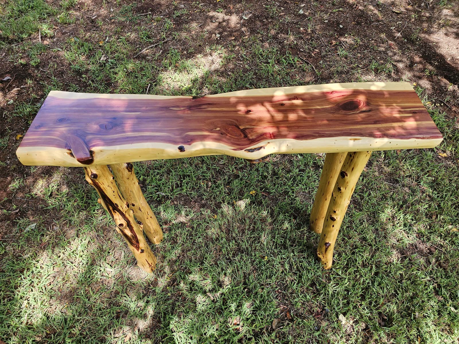 Live-edge Eastern red cedar slab table standing on cedar staves in the grass